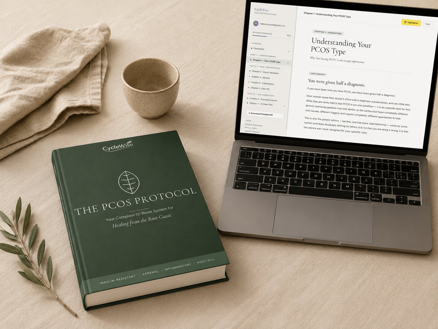 The PCOS Protocol printed workbook on a desk beside an open laptop displaying the digital guide
